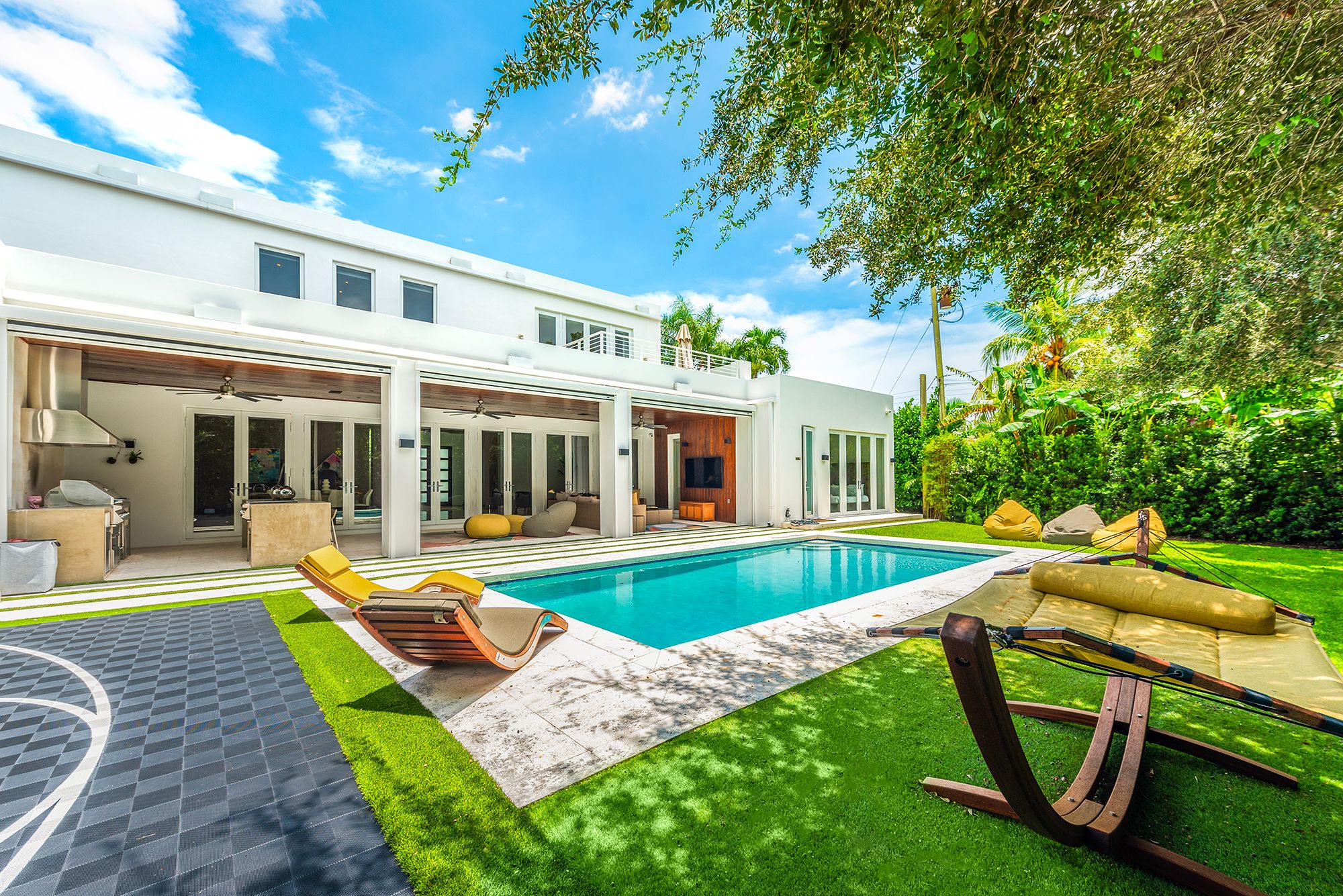 The pool area for Villa Amani with a basketball court, lounge seating, hammock, and a spacious well maintained yard in Miami with Luxuri Villas.