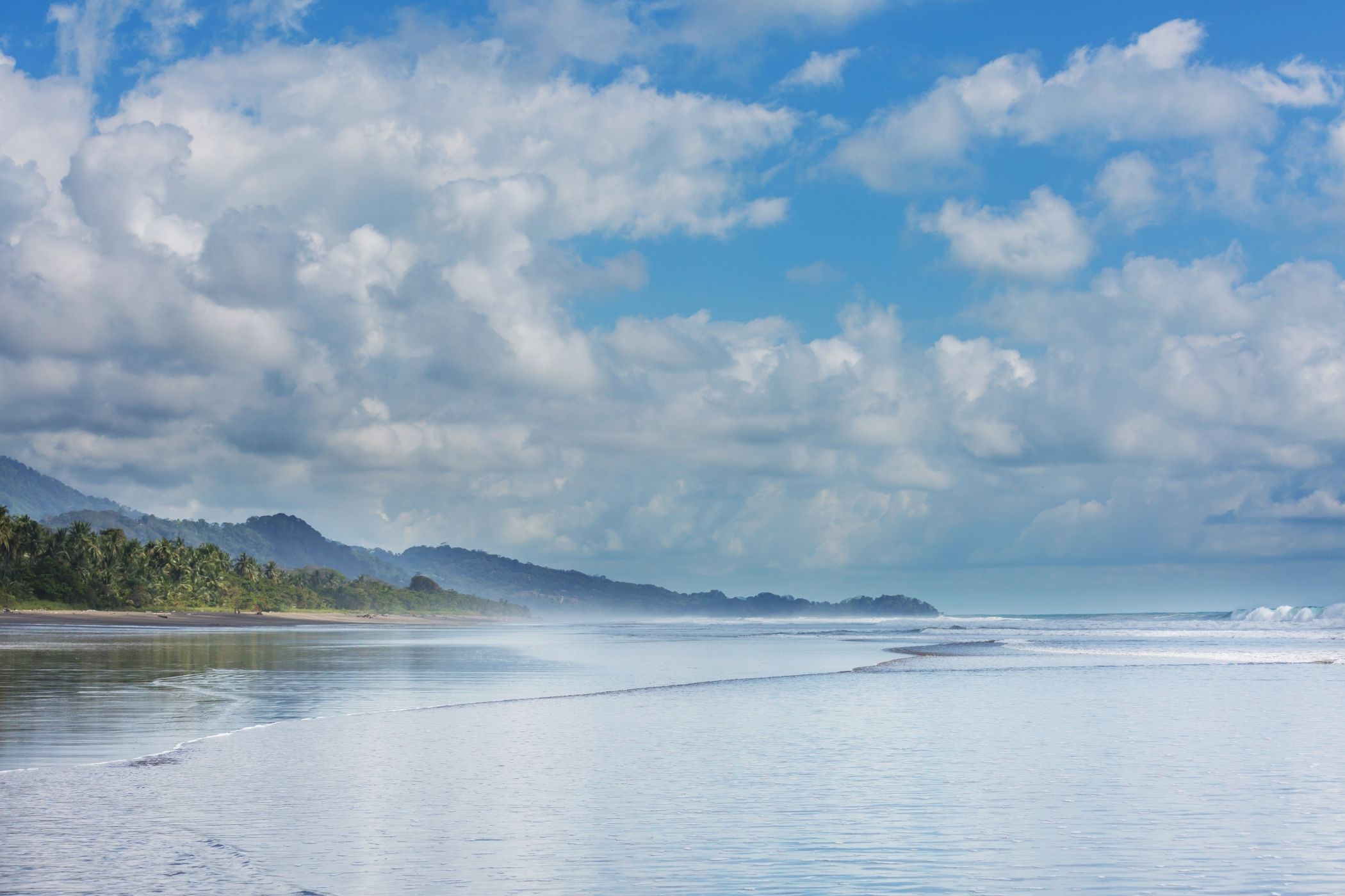 Beautiful tropical Pacific Ocean coast in Costa Rica on a sunlight day with puffy white clouds.