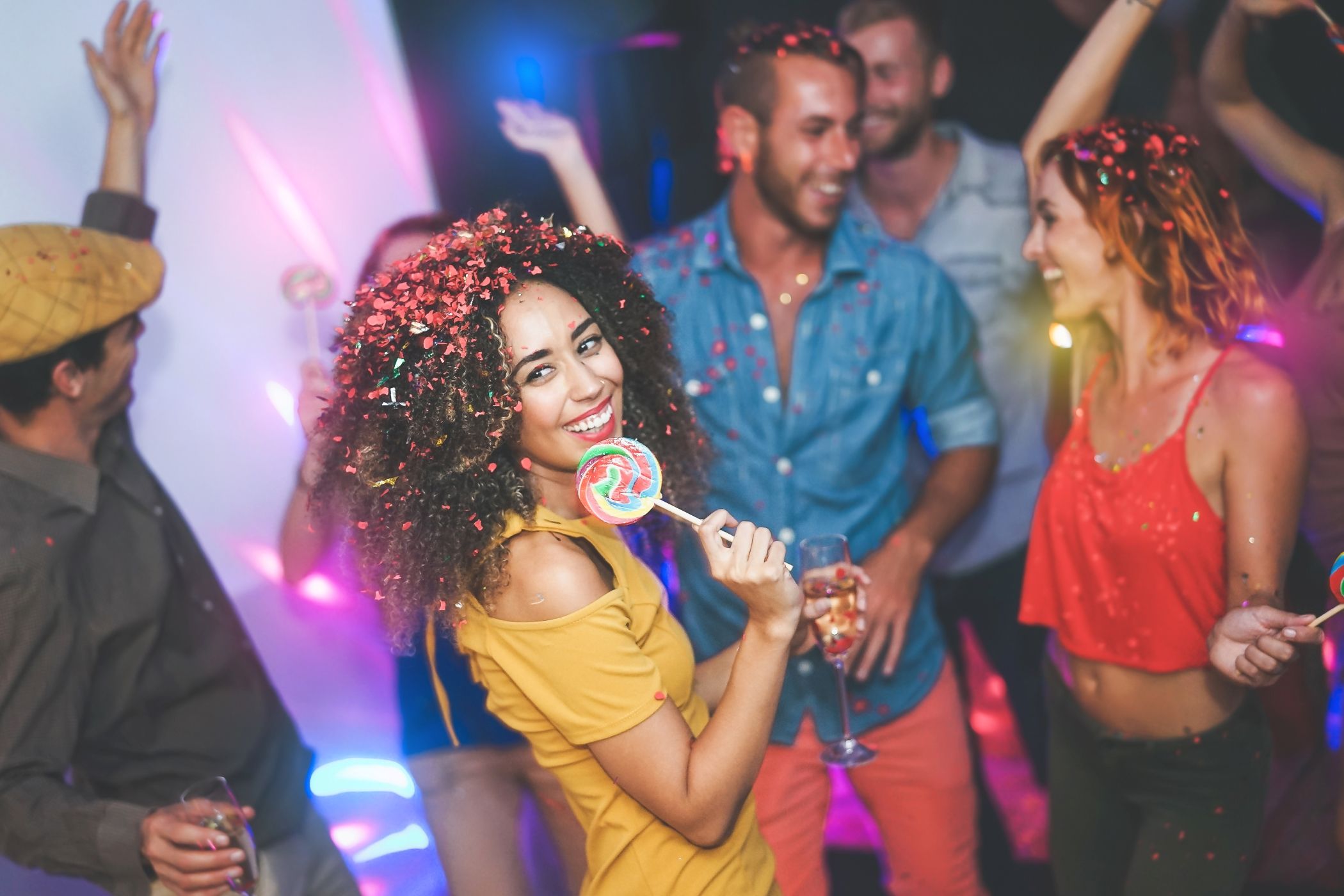 Group of friends dancing and celebrating at a lively Miami nightclub, with confetti in the air and vibrant lighting setting the energetic party scene.