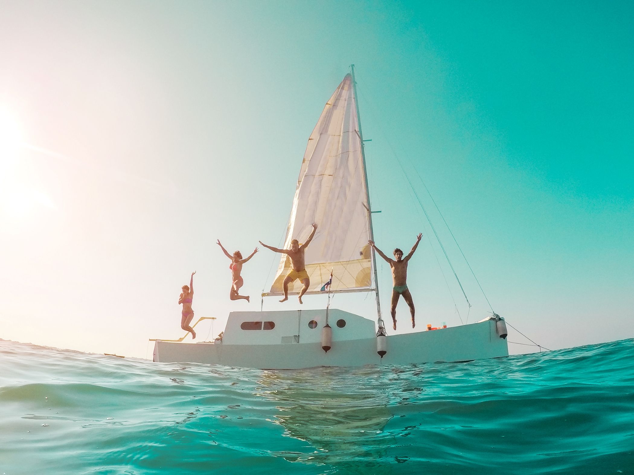 Happy crazy friends diving from sailing boat into the sea near Miami.
