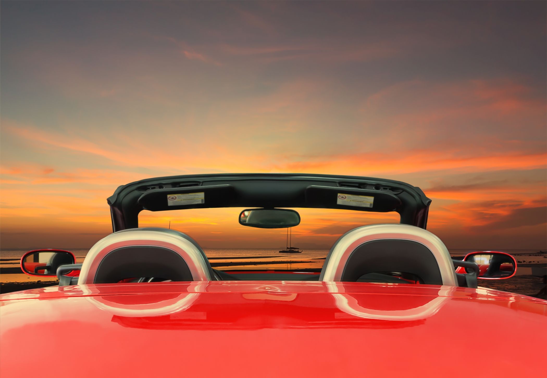Red convertible overlooking the Miami sunset with ocean views, capturing the essence of a luxurious drive along the coastline as the day fades into night.